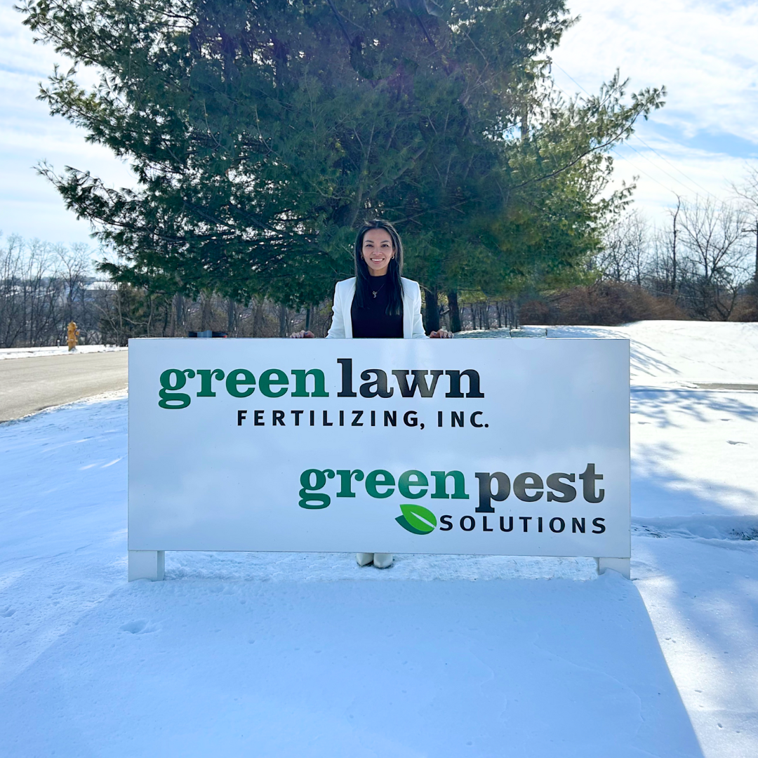 Ying Bruschi standing outside Green Lawn Fertilizing sign